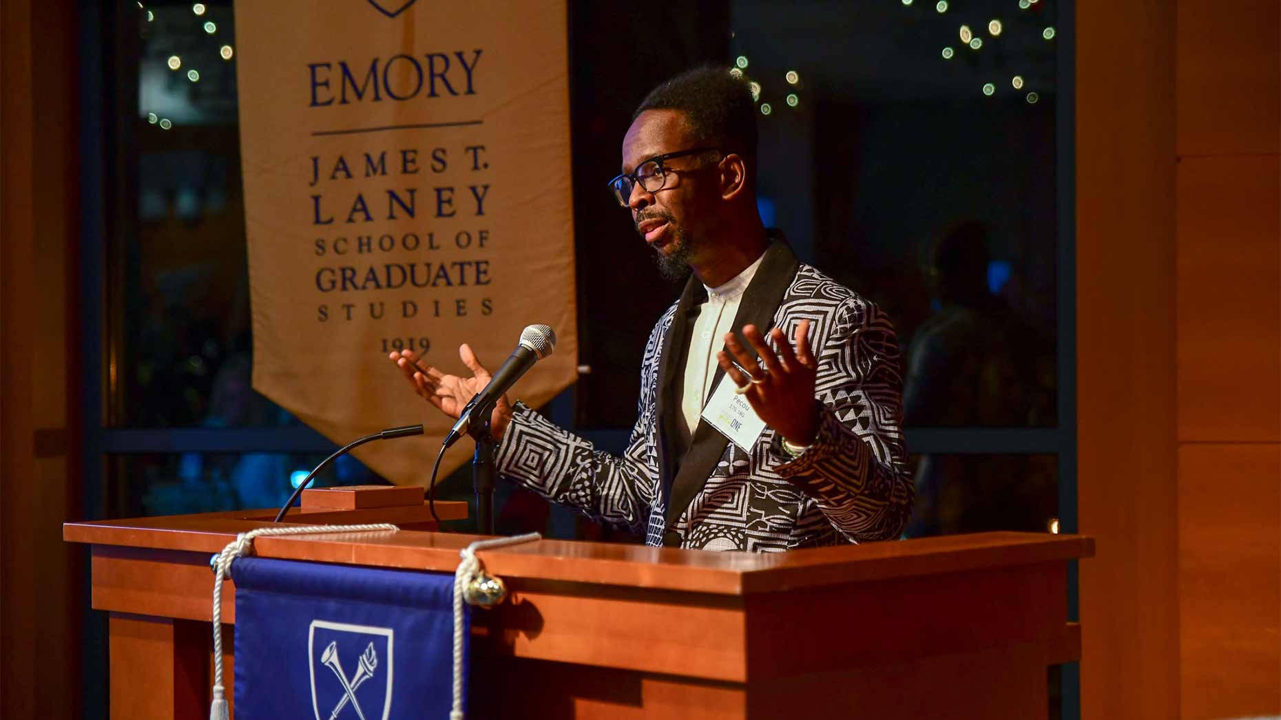 Male speaker gives lecture behind a podium on an Emory University stage.